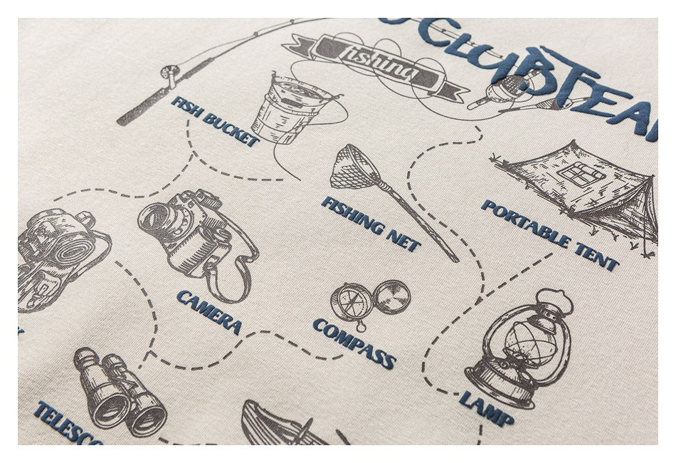 Close-up of cream hoodie artwork with illustrated camping and fishing gear and English labels, including camera, compass, and