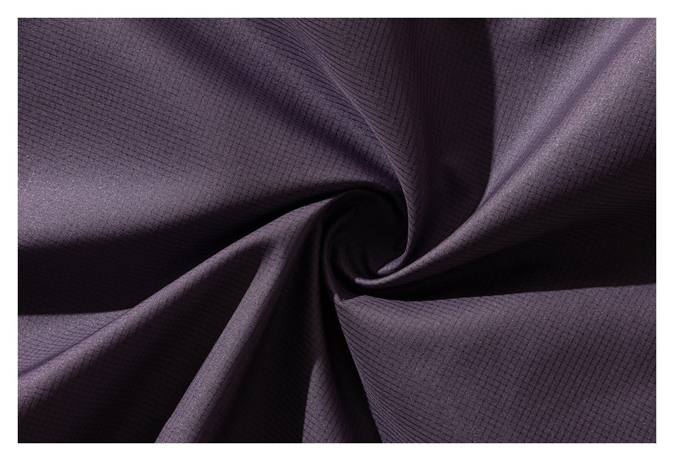 Close-up of dark plum fabric arranged in folds, showing a subtle grid texture.