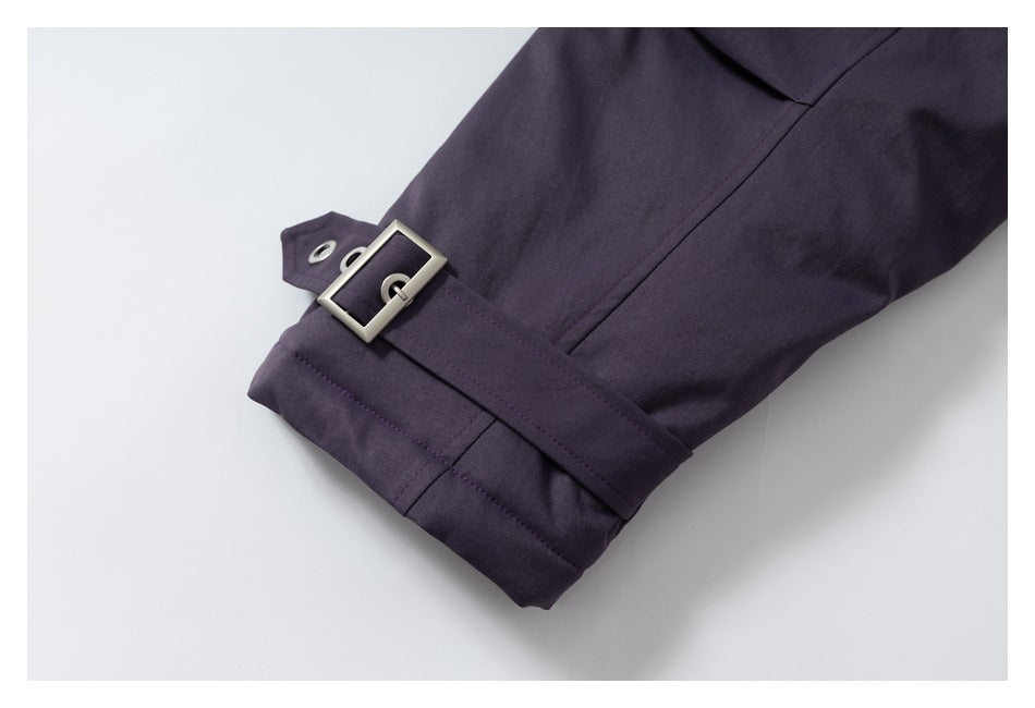 Close-up of a dark purple coat cuff with a strap, rectangular metal buckle, and eyelets.