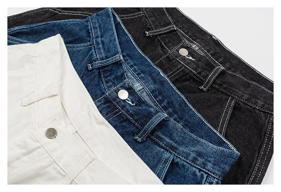 Close-up of denim shorts in white, blue, and black, showing waistbands, belt loops, and button closures.