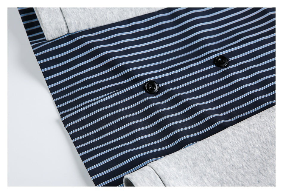 Close-up of the navy blue striped inner panel and two black buttons against light gray garment fabric.