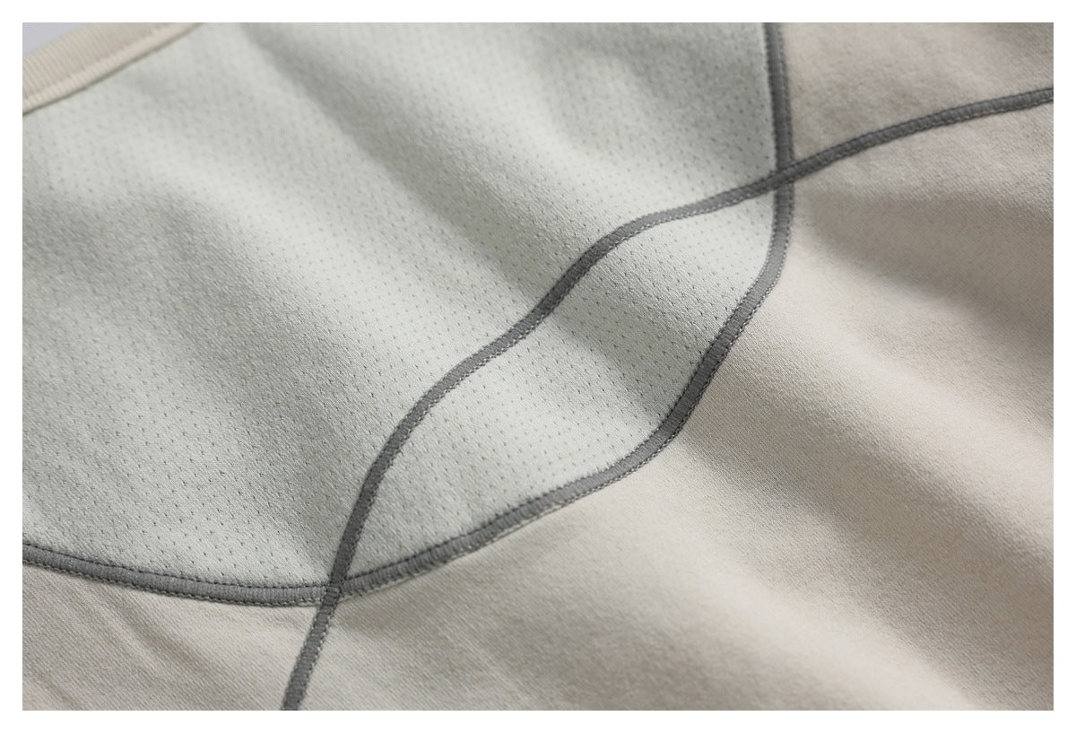 Close-up of a perforated light beige panel bordered by curved dark gray seams against smooth fabric.