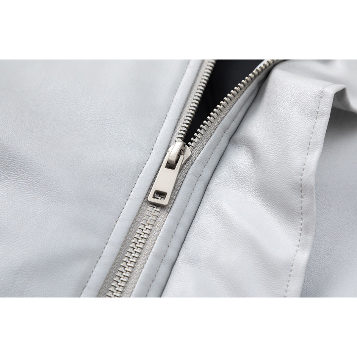 Close-up of a silver zipper and stitching on a pale gray jacket.