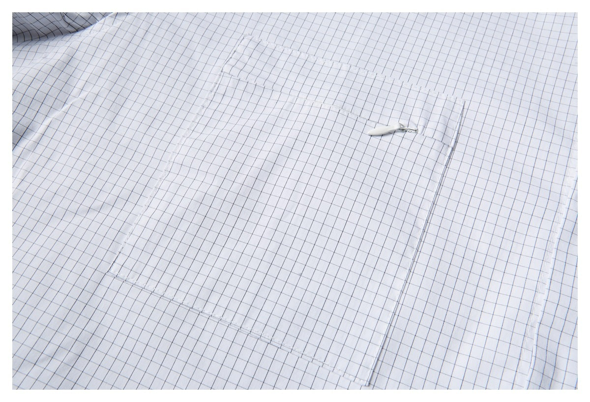Close-up of a large patch pocket with a small zipper on the white grid-check shirt.