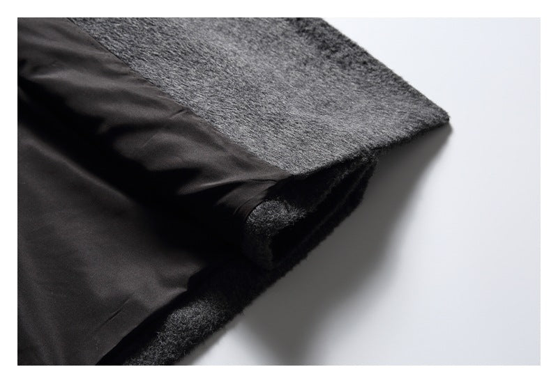 Close-up of a charcoal gray fuzzy coat edge folded back to show its smooth black lining.