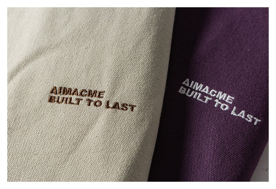 Close-up of embroidered lettering on off-white and purple jacket fabric.