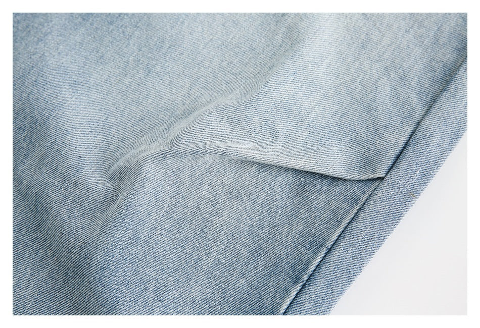 Close-up of a stitched seam and folded edge on light blue denim.