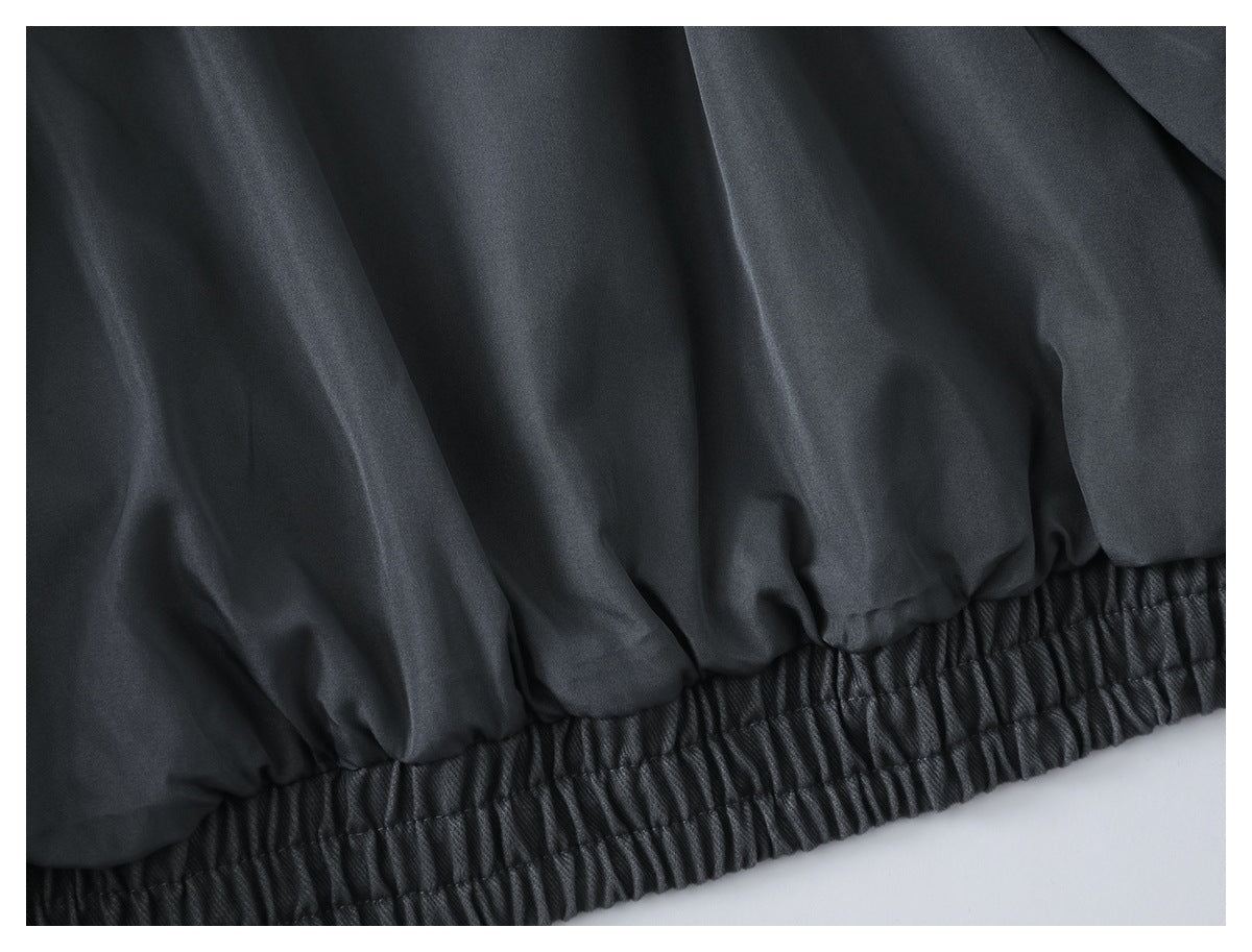 Close-up of the charcoal jacket’s gathered elastic hem and fabric folds.