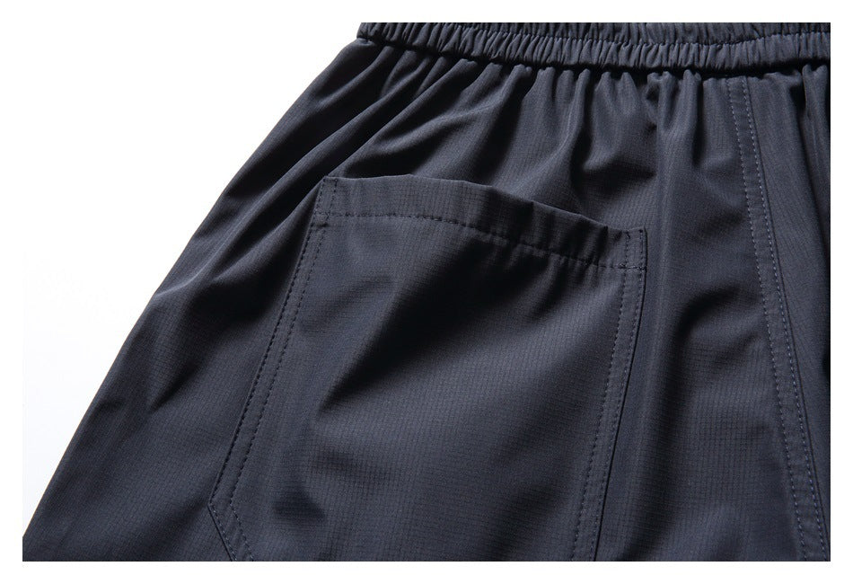 Close-up of dark navy pants showing an elastic waistband and a stitched rear pocket.