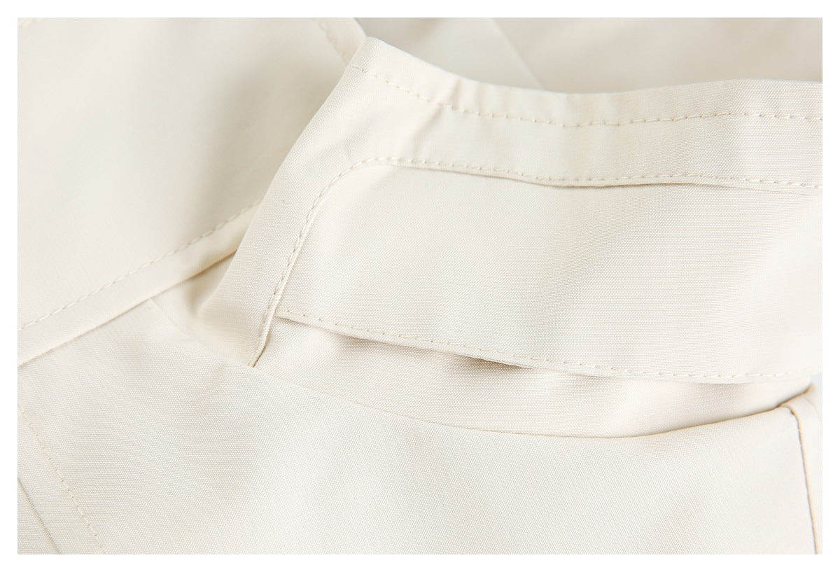 Close-up of cream garment fabric with a folded edge and neat stitching.