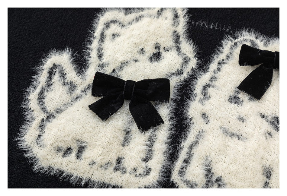 Close-up of fuzzy white cat motifs and black bows on a black sweater.