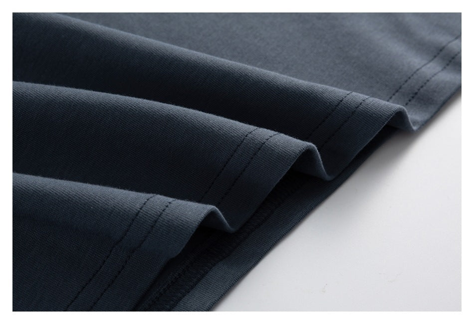 Close-up of layered, double-stitched hems on dark slate-gray fabric.