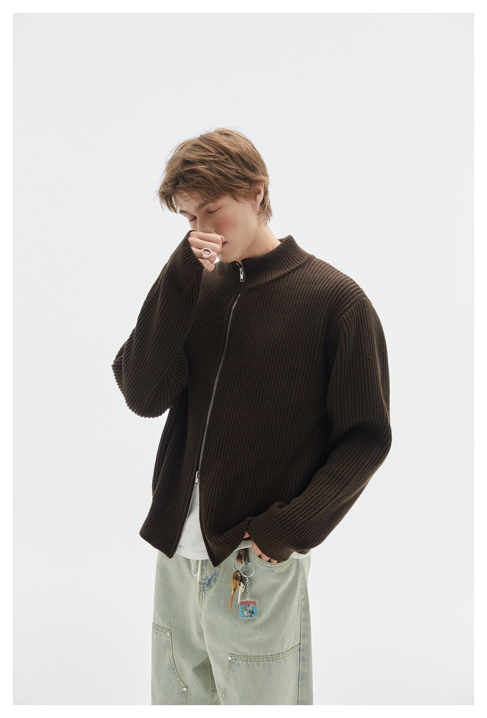 Model wearing a dark brown ribbed zip-front cardigan over a white shirt with light-wash jeans.