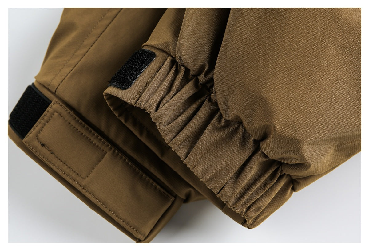 Close-up of a brown jacket cuff with gathered fabric and black hook-and-loop adjustment tabs.