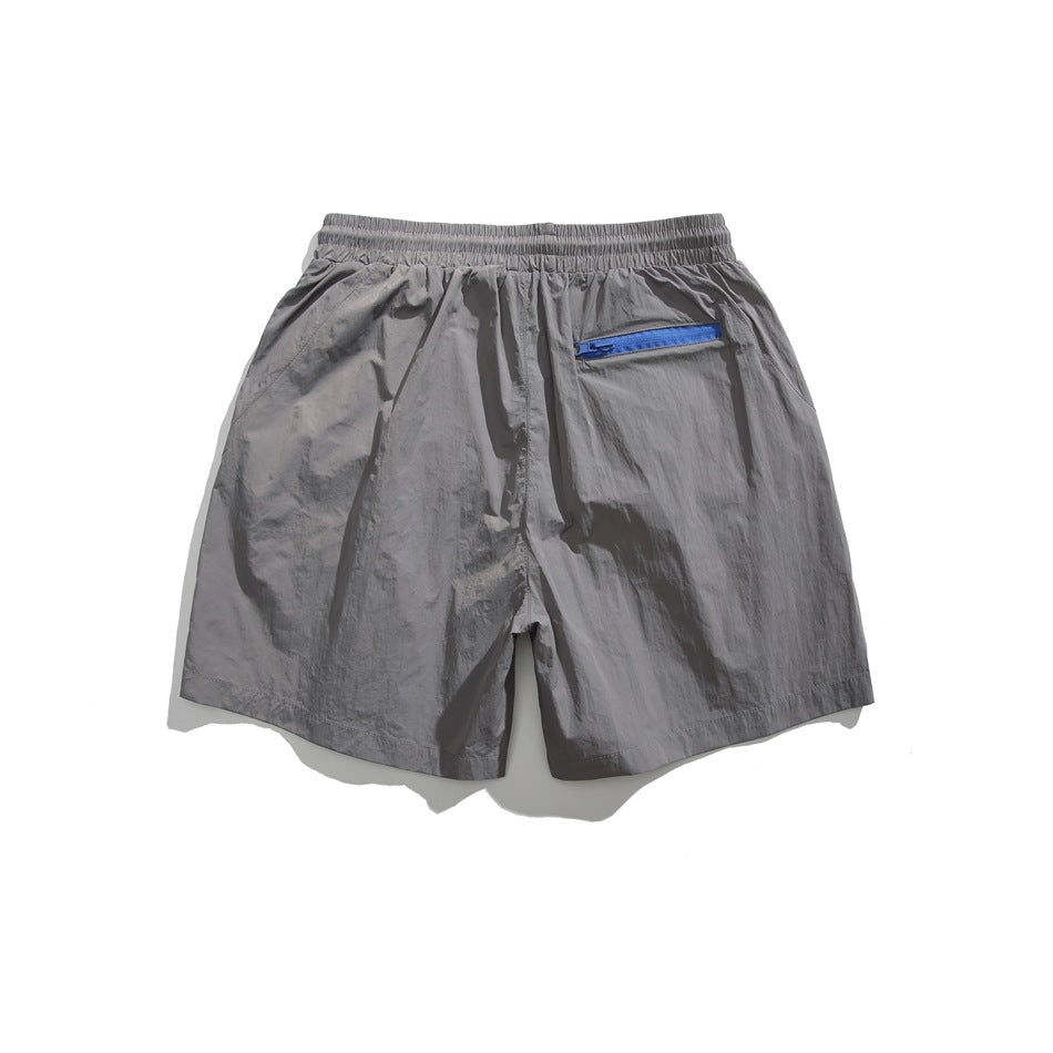 Back view of gray shorts with an elastic waistband and blue zip pocket.