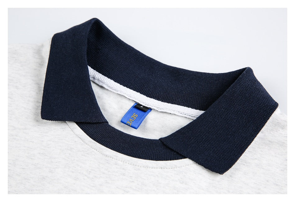 Close-up of a navy polo collar, white heathered shirt fabric, and a small blue neck label.