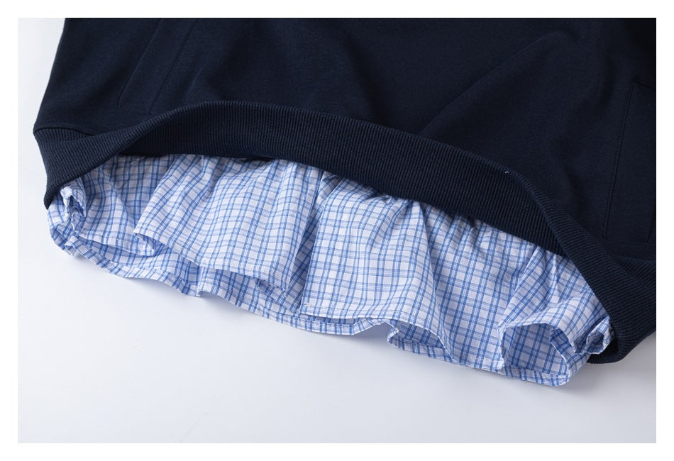 Close-up of a navy sweatshirt hem layered over a blue-and-white plaid shirt hem.