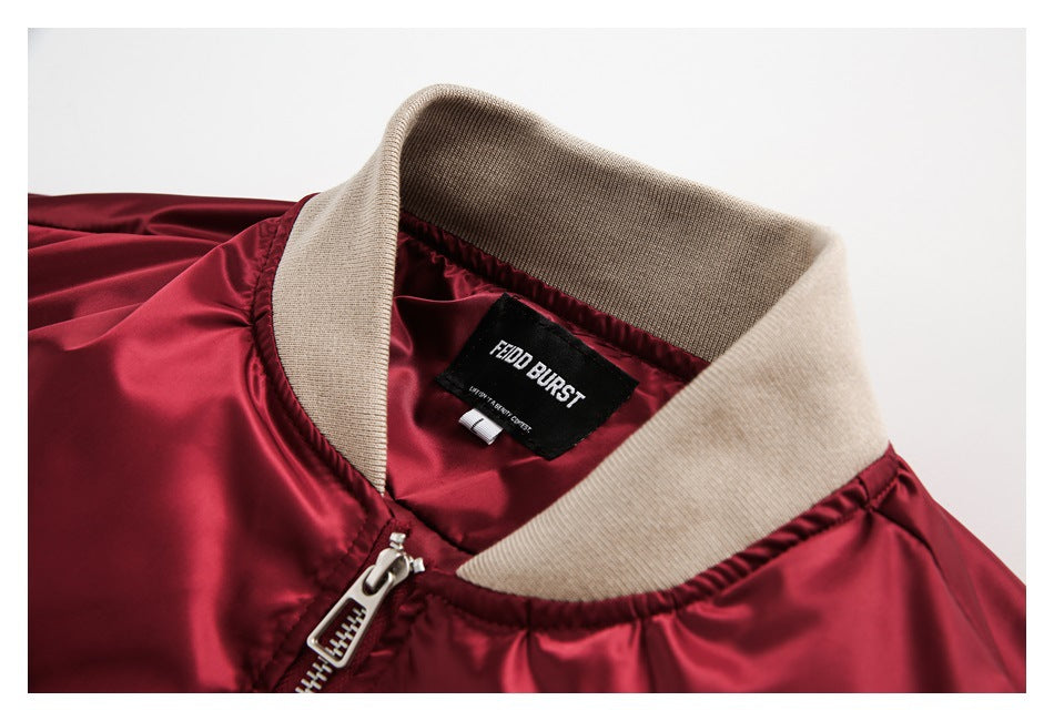 Close-up of a burgundy bomber jacket's beige ribbed collar, zipper, and sewn-in neck label.
