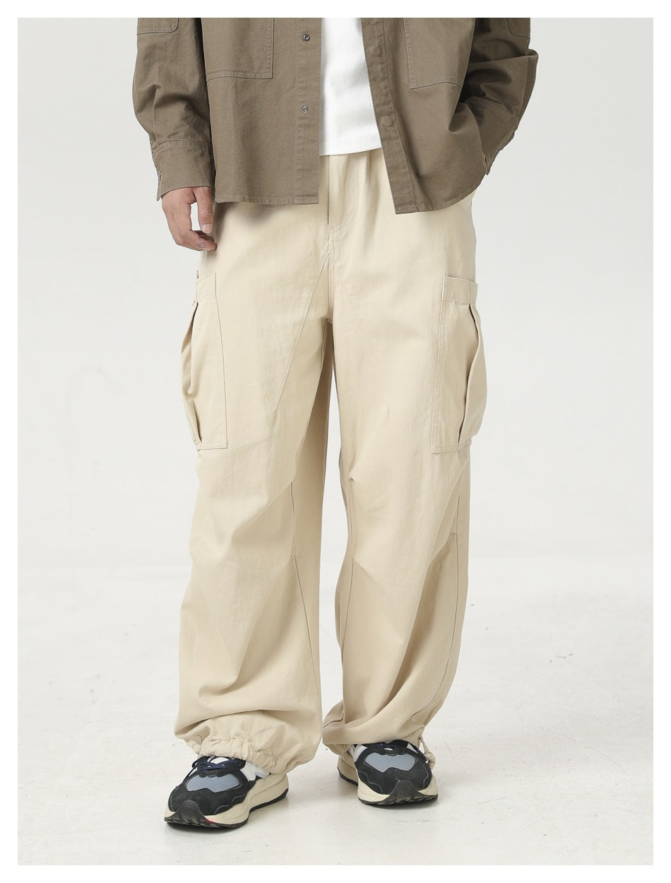Front view of a model wearing loose cream cargo pants with large side pockets and gathered ankle cuffs.