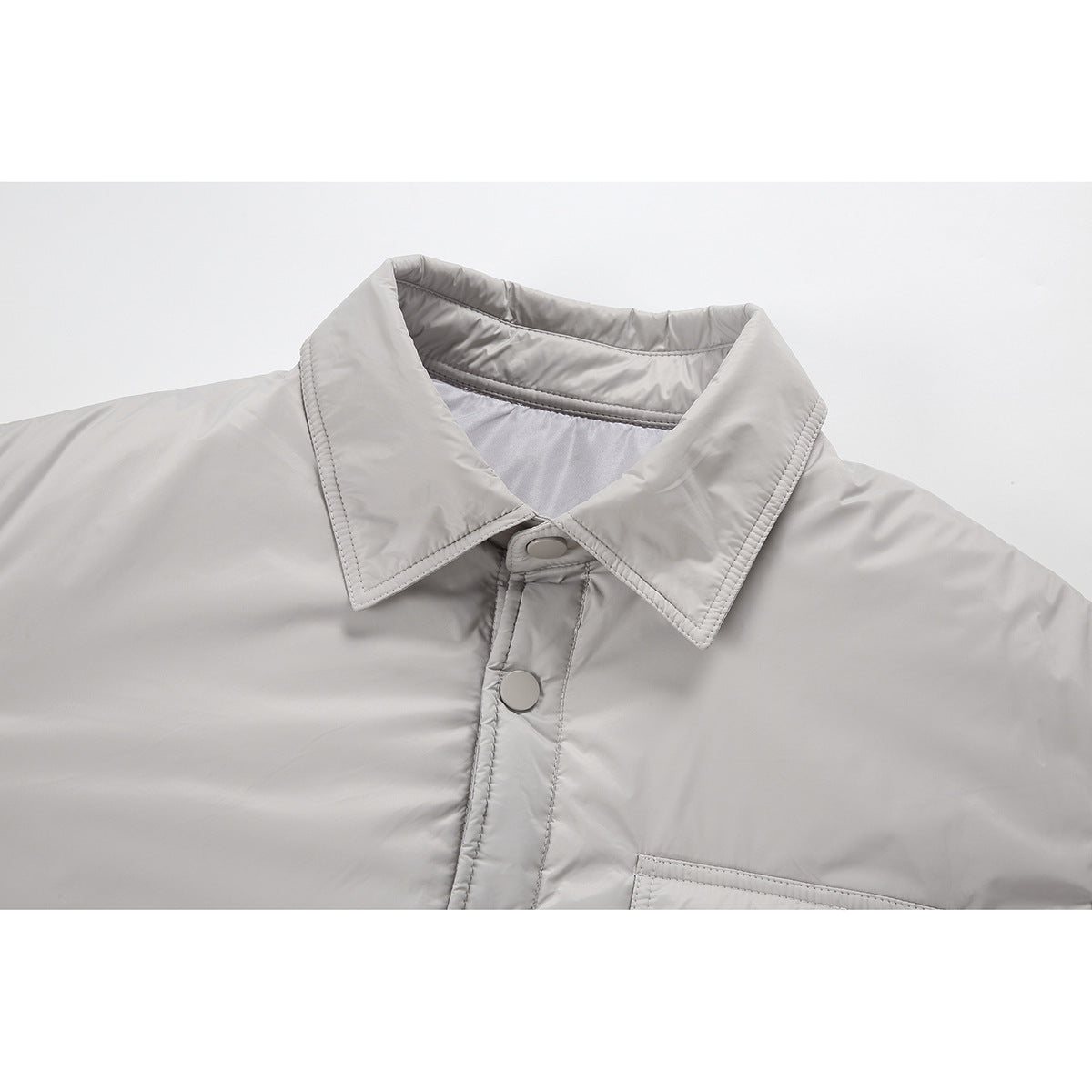 Close-up of a light gray jacket’s pointed collar, snap-button placket, and chest pocket edge.