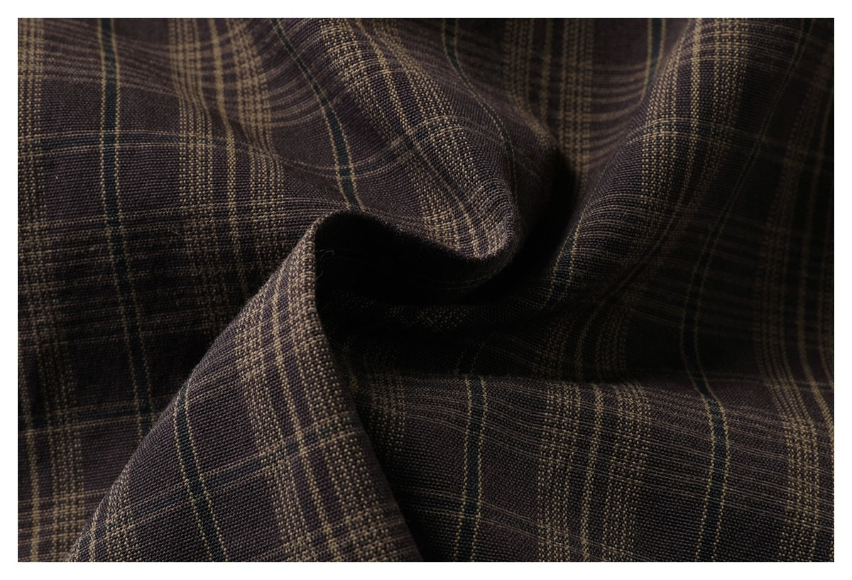 Close-up of dark brown plaid fabric draped into folds, showing tan intersecting lines and woven texture.