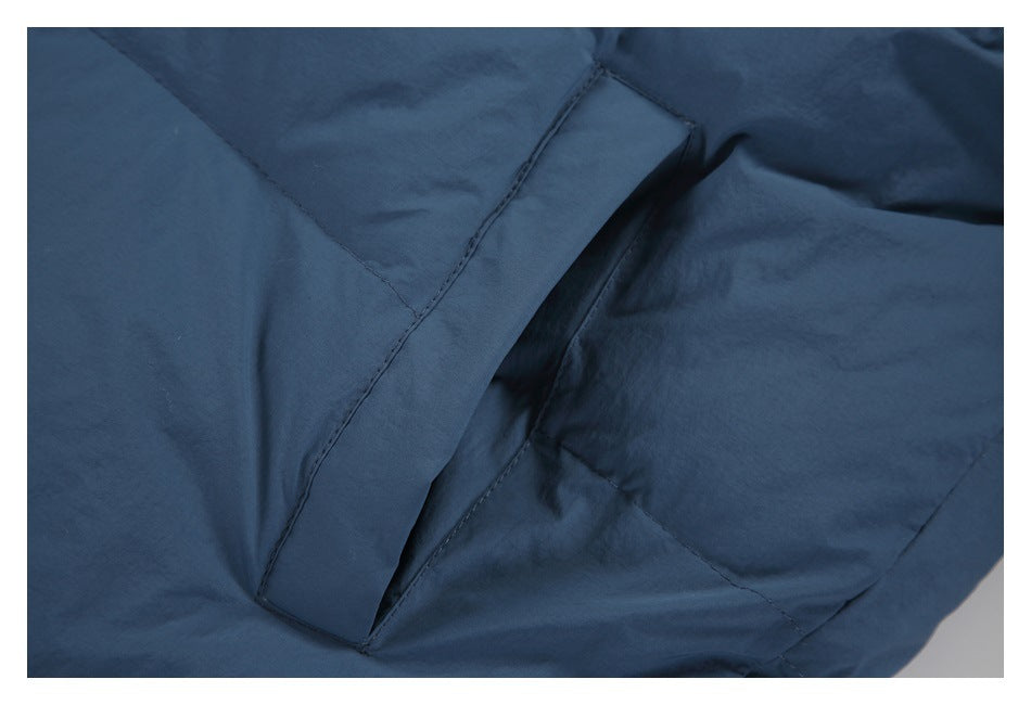 Close-up of a slanted pocket opening and stitching on the slate-blue jacket.