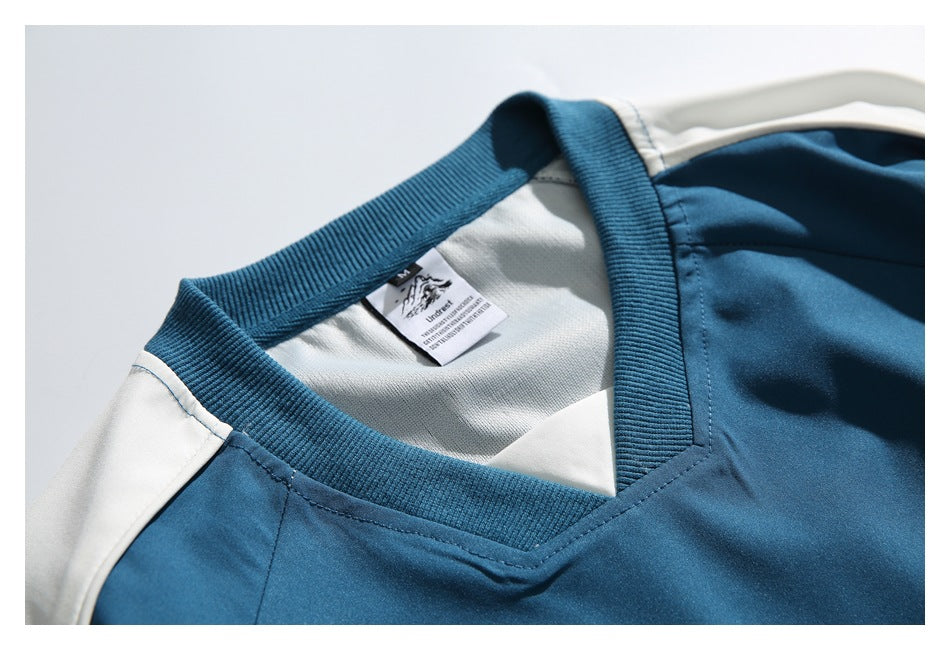 Close-up of the blue pullover's ribbed V-neck, inner label, and white shoulder panel.
