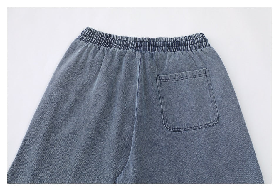 Close-up back view of blue-gray denim bottoms with an elasticated waistband and one patch pocket.