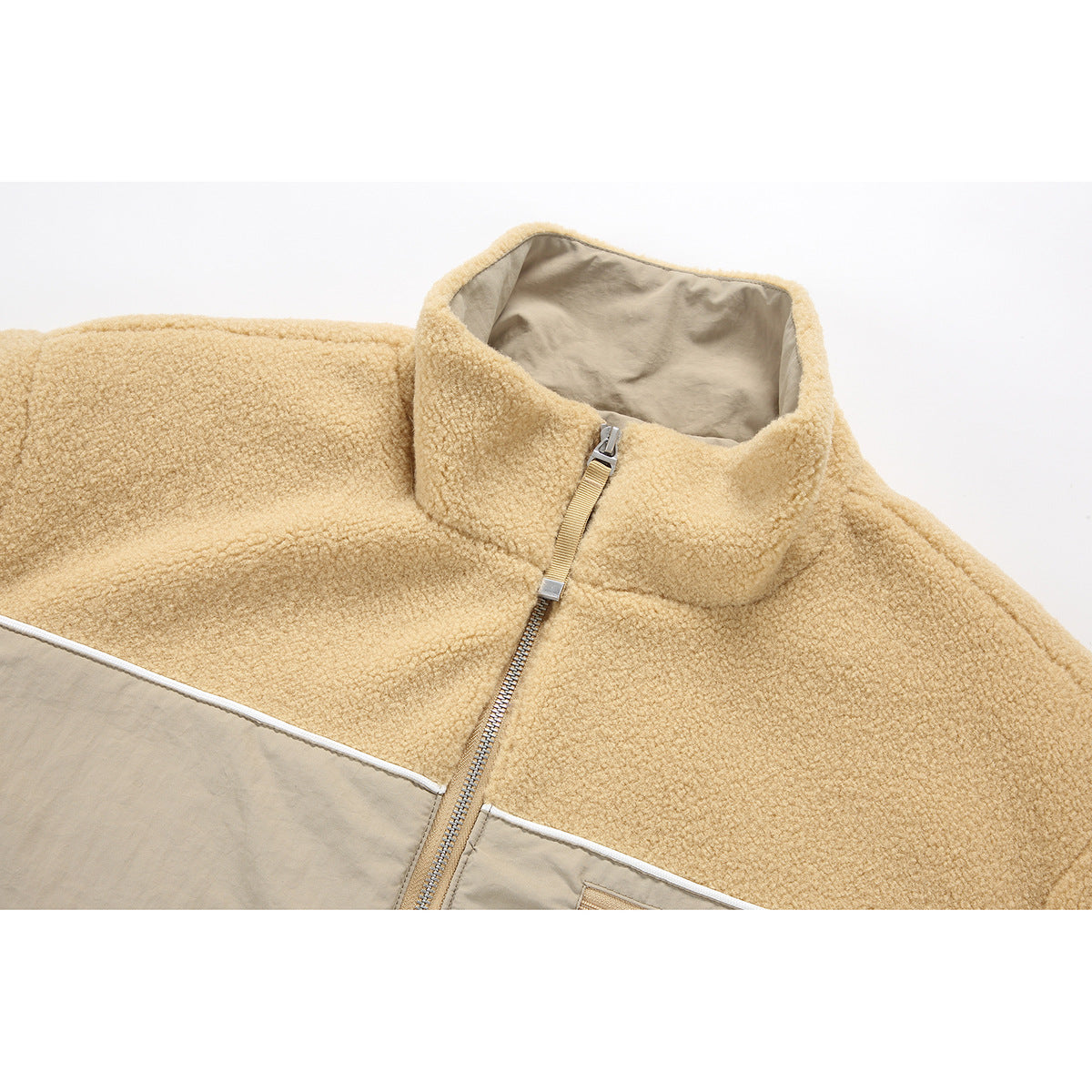 Close-up of a tan fleece jacket collar, metal front zipper, and beige contrast panels with white piping.