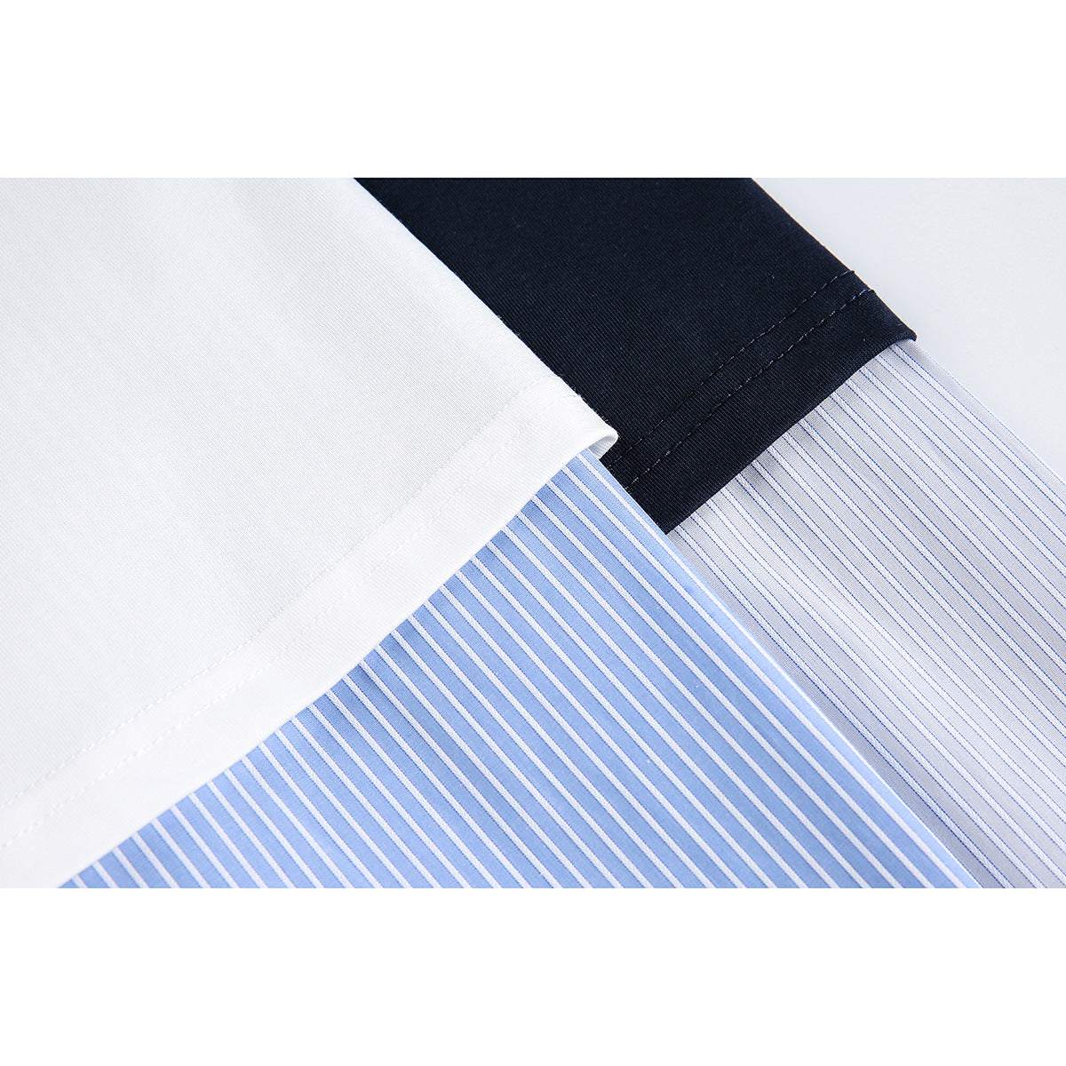 Close-up of white and navy shirt hems overlapping blue-and-white striped fabric.
