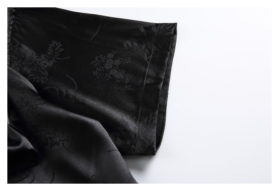 Close-up of the wide sleeve and cuff of a black shirt with a subtle floral pattern.