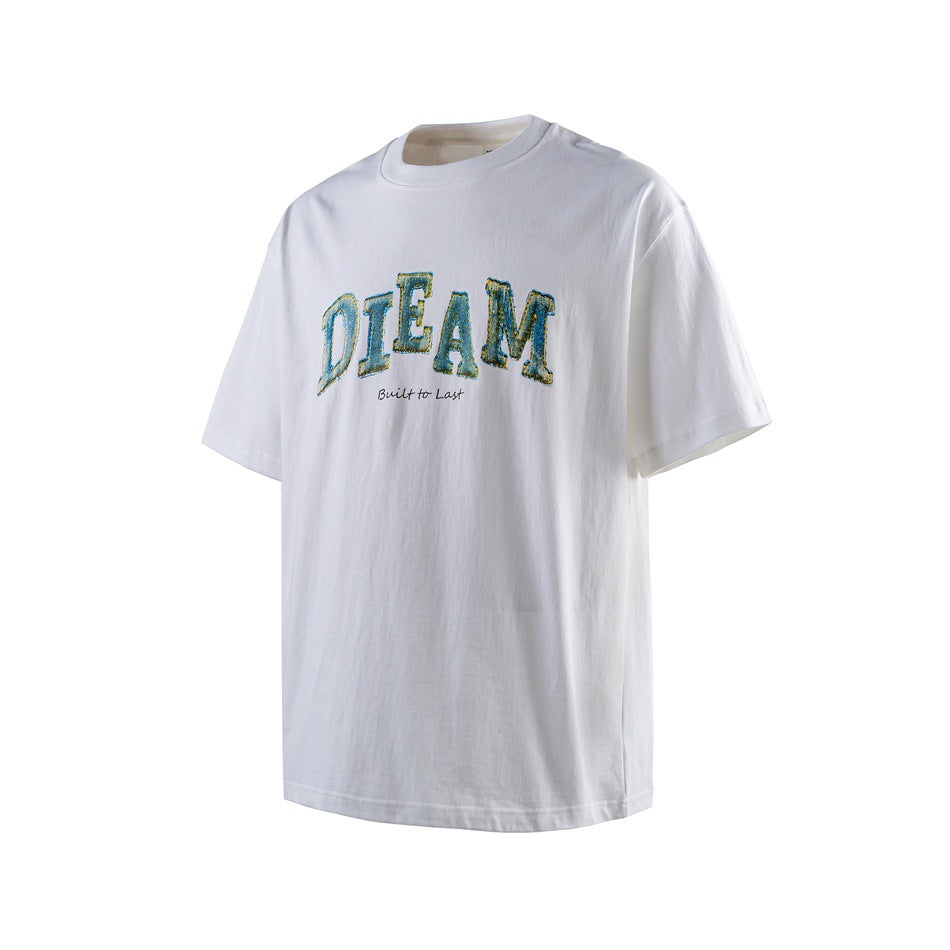 White short-sleeve crew-neck T-shirt with blue-green arched DIEAM graphic and Built to Last script, angled view