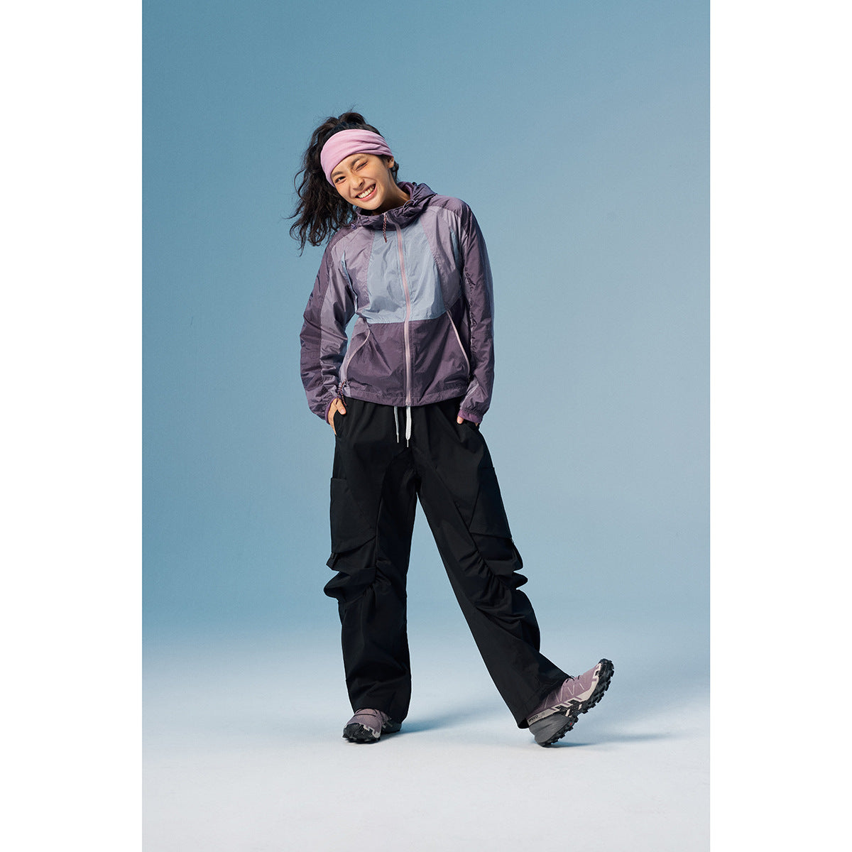 Model wearing a purple and pale blue color-block hooded jacket with black cargo pants.