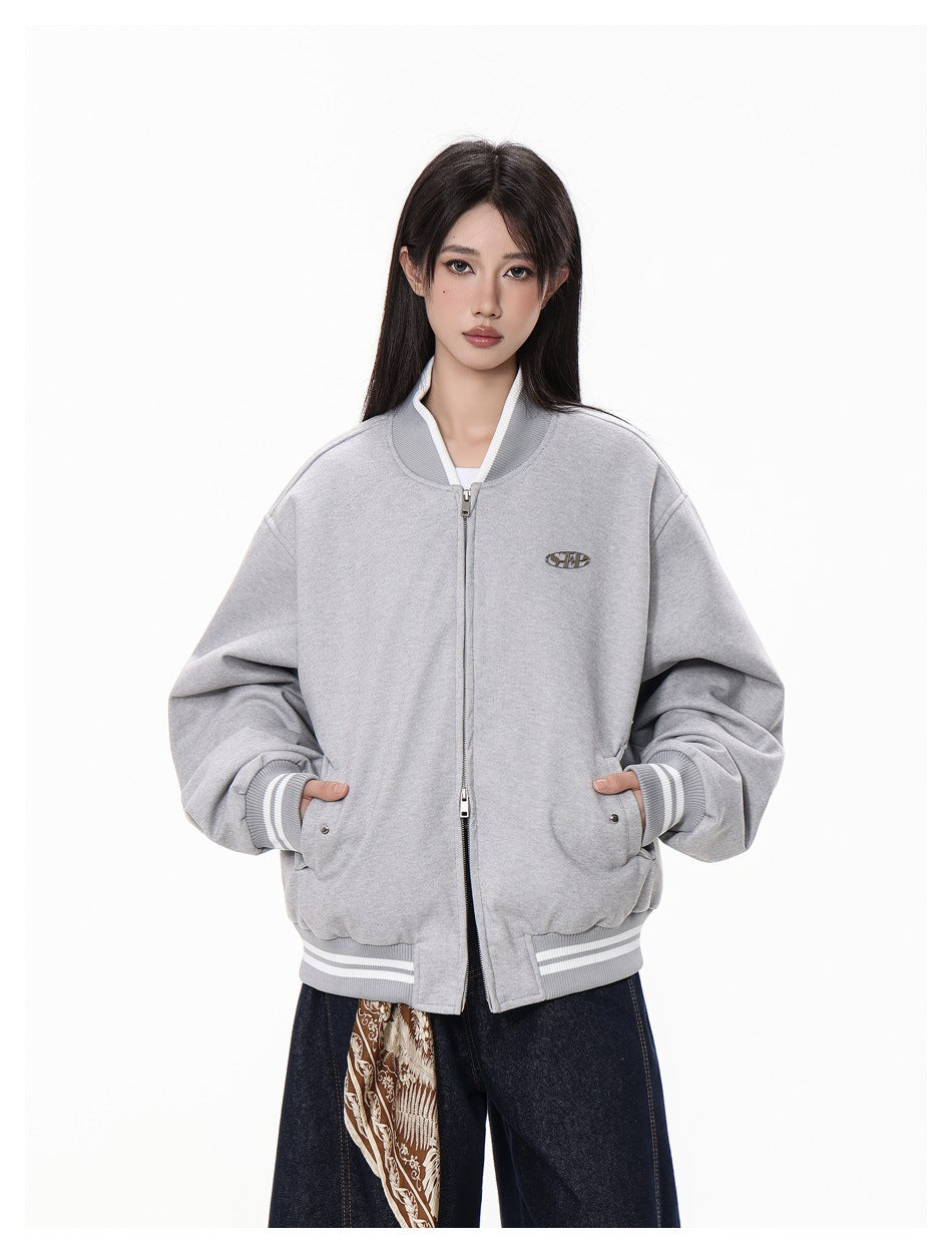 Front view of a model wearing a light gray oversized zip-up bomber jacket with striped ribbing, snap pockets, and a small