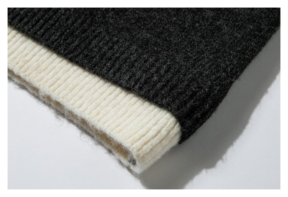 Close-up of the sweater's dark charcoal knit body and wide cream ribbed hem.