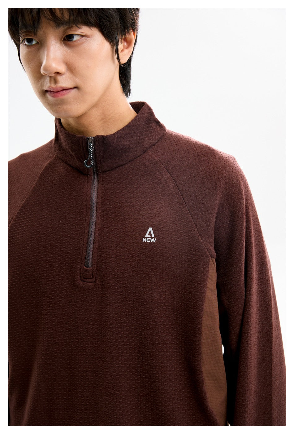Close-up of the burgundy pullover's textured front, quarter zipper, stand collar, and small chest logo.