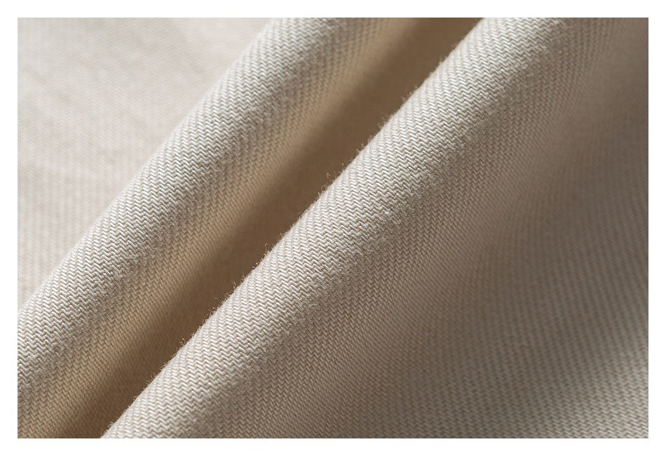 Extreme close-up of cream-colored shirt fabric folded into ridges, showing its woven texture.