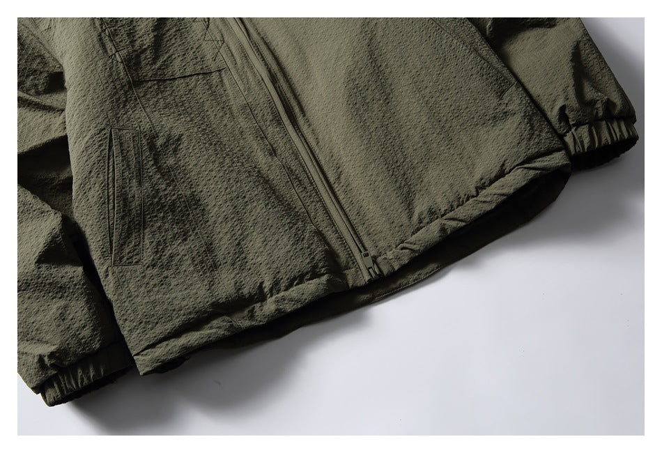 Partial flat-lay front of an olive textured zip jacket, showing pockets, zipper and elastic cuffs.