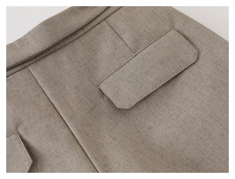 Close-up of a flap pocket and seam on beige-gray trousers.