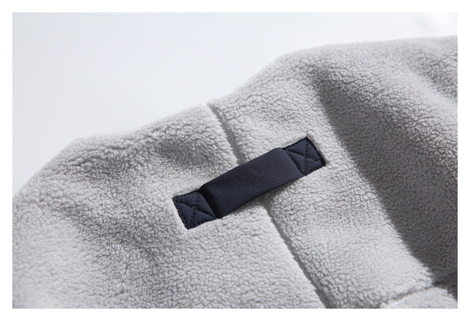 Close-up of light gray plush fleece with a short black fabric tab sewn across a seam.