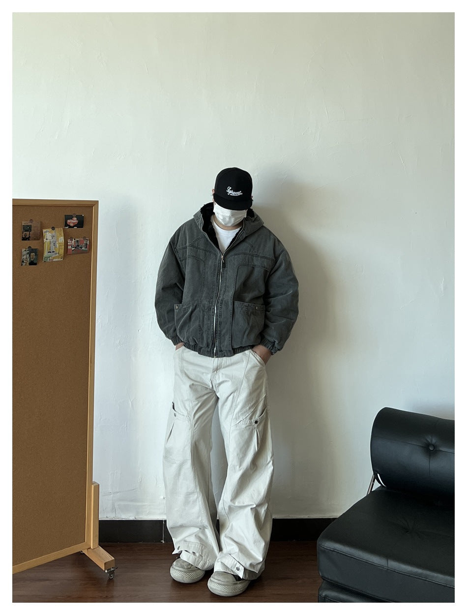 Front view of a person wearing a dark charcoal hooded zip jacket with large pockets and cream cargo pants.