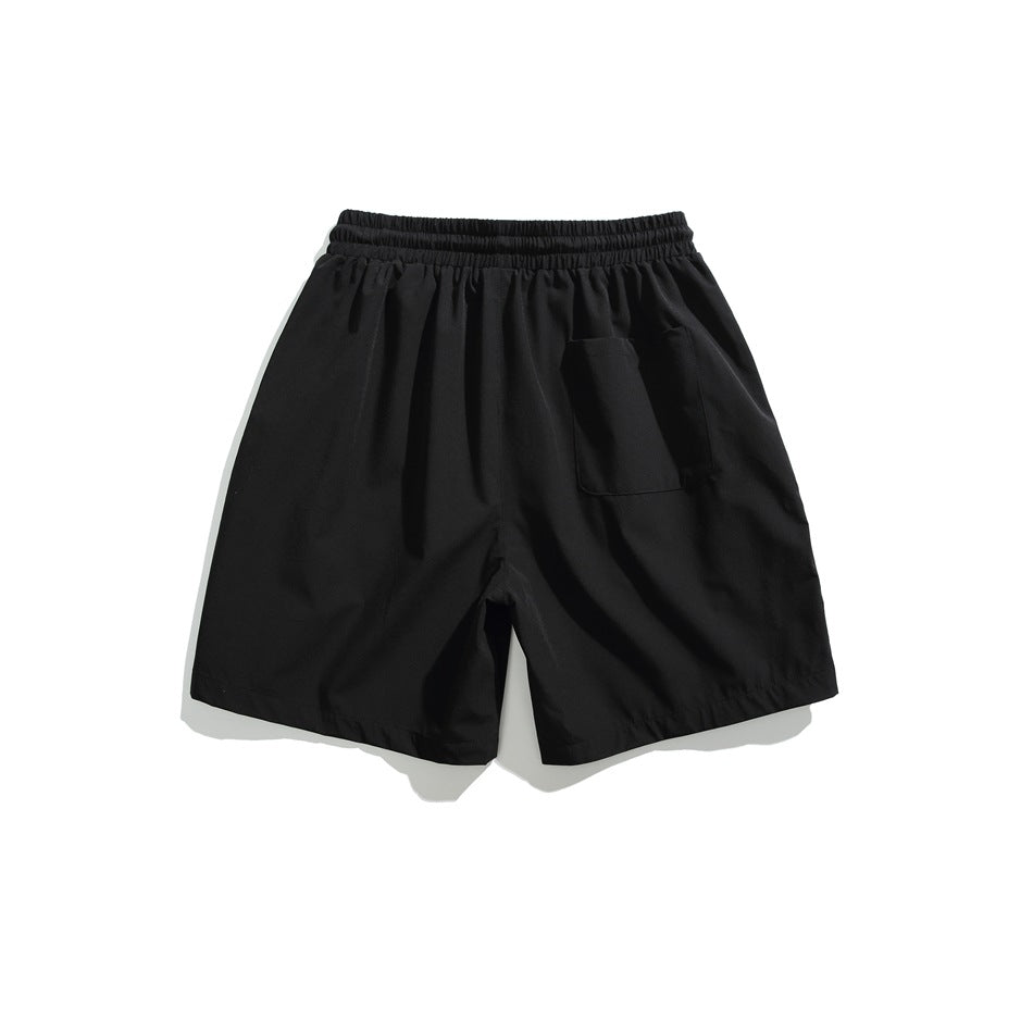 Back view of black shorts with an elastic waistband and a single patch pocket.