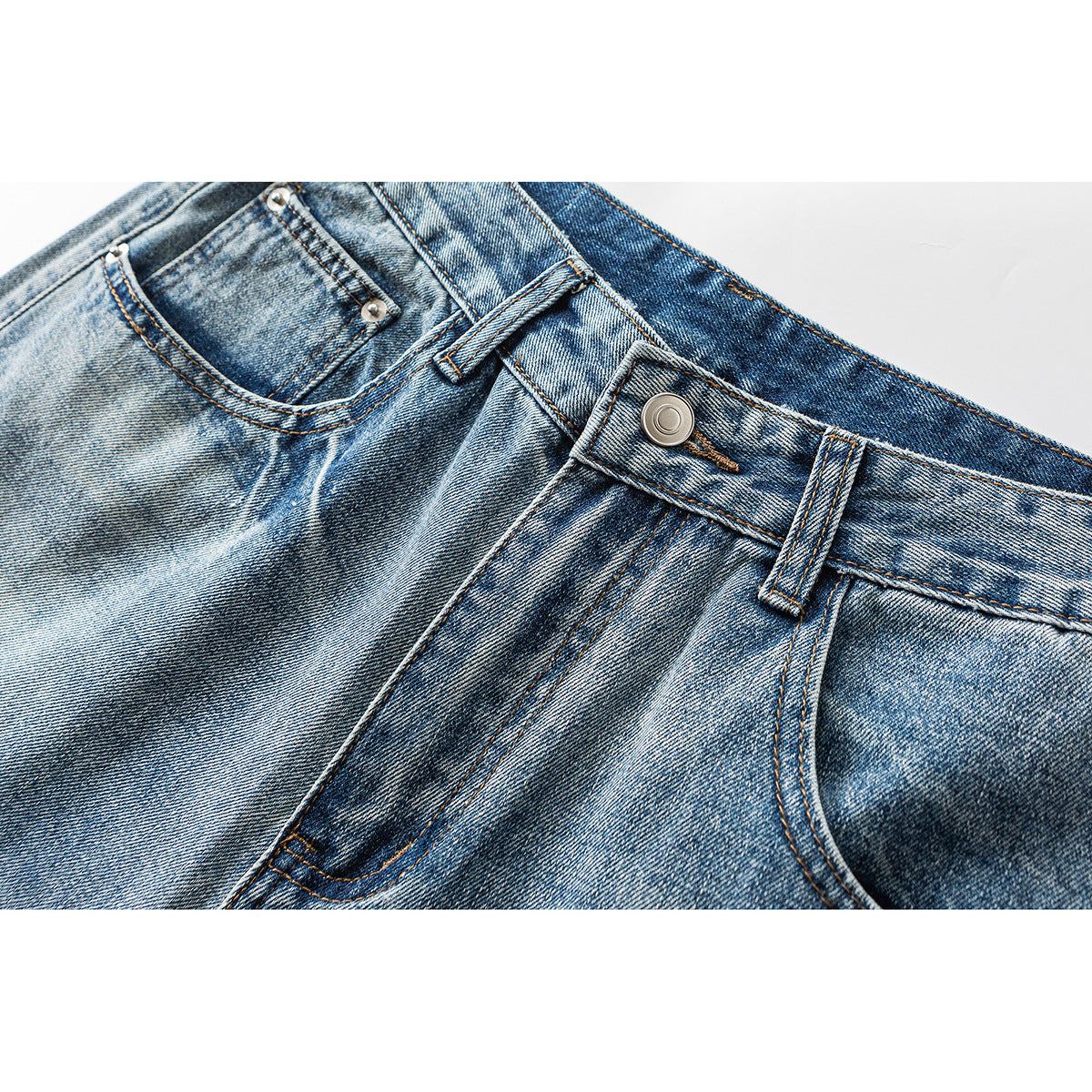 Close-up of blue faded jeans showing the waistband, metal button, belt loop and front pockets.