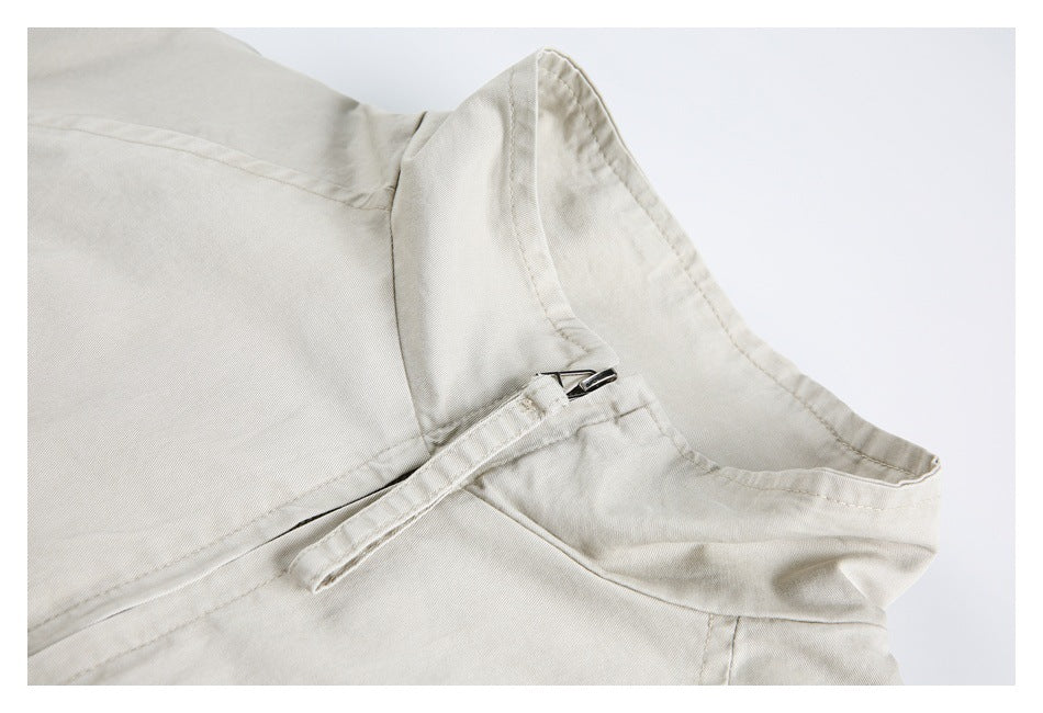 Close-up of a cream garment's curved waist area with a short zipper and stitched band.