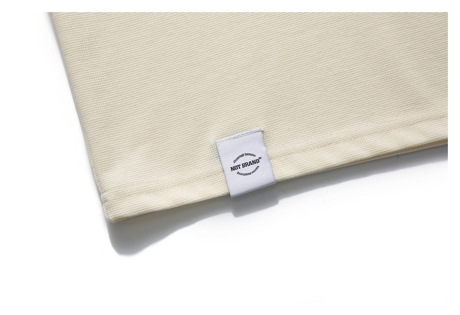 Close-up of the ivory polo's hem and a small sewn white label.