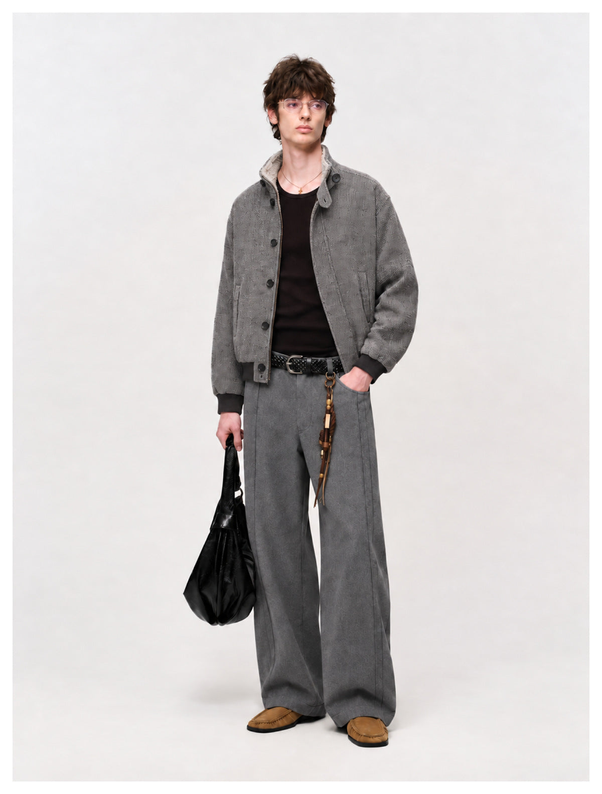 Model wearing gray wide-leg trousers with a braided belt, gray bomber jacket, black top and tan loafers