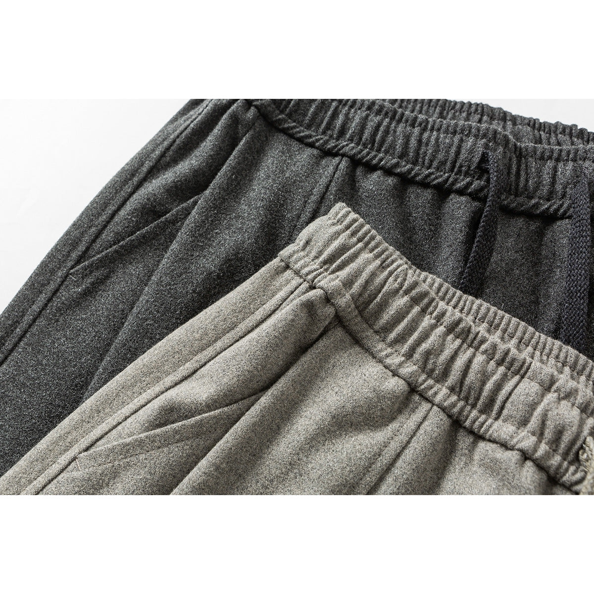 Close-up of light gray and charcoal pants showing their elastic waistbands and drawstrings.