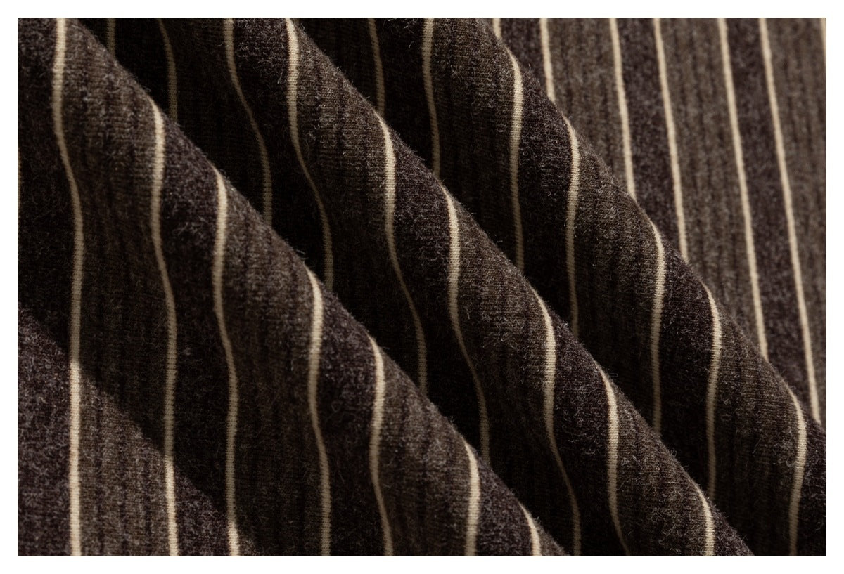 Macro view of the dark brown fabric and thin cream stripe pattern on a shirt.