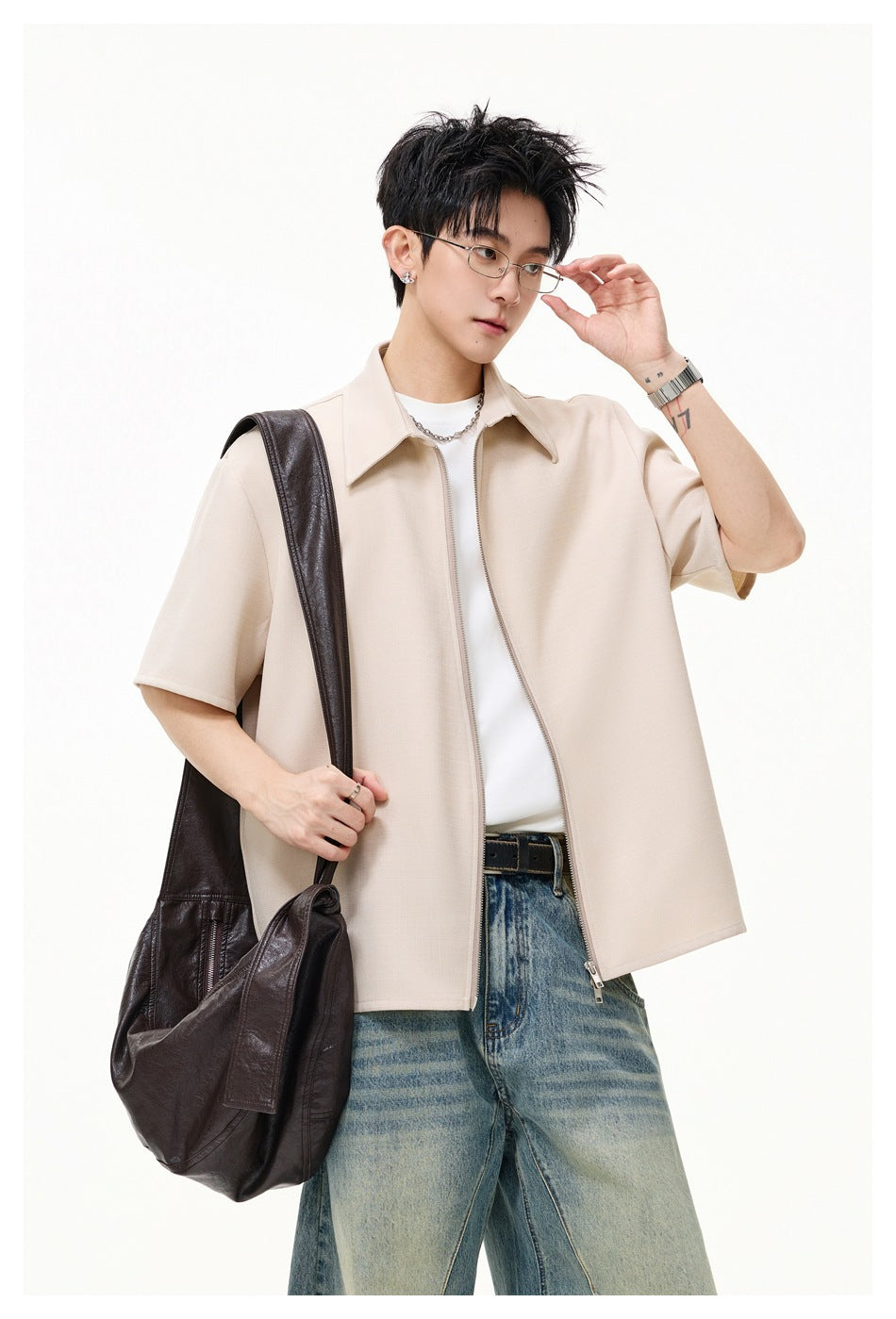 Front view of a model wearing a light beige short-sleeve collared zip-front shirt over a white tee.