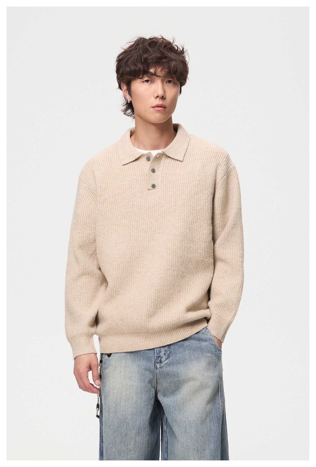 Closer view of a model wearing a beige ribbed sweater with a pointed collar and three-button placket.